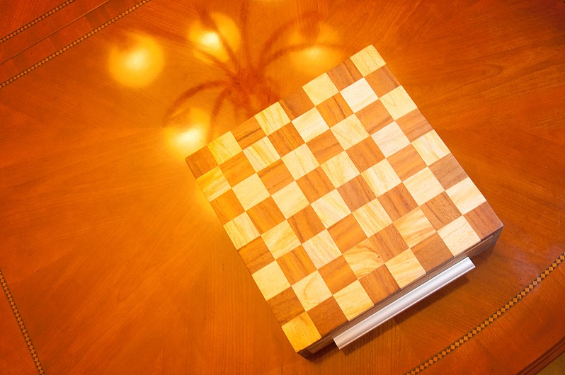 Overhead shot of the finished wooden chessboard on a coffee table, warm ambient light