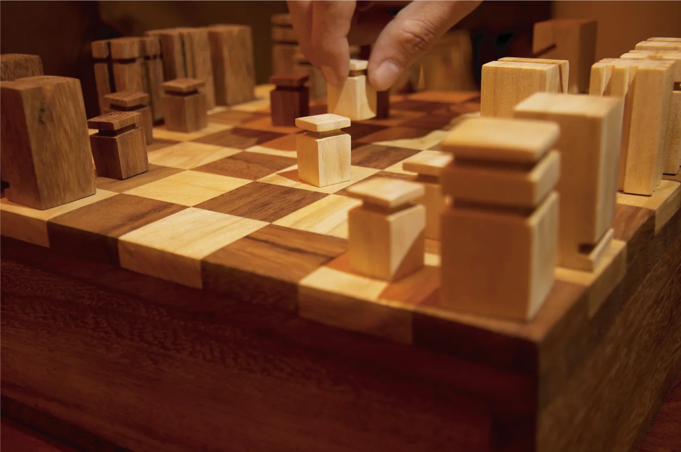 A hand moving a chess piece across the finished board mid-game