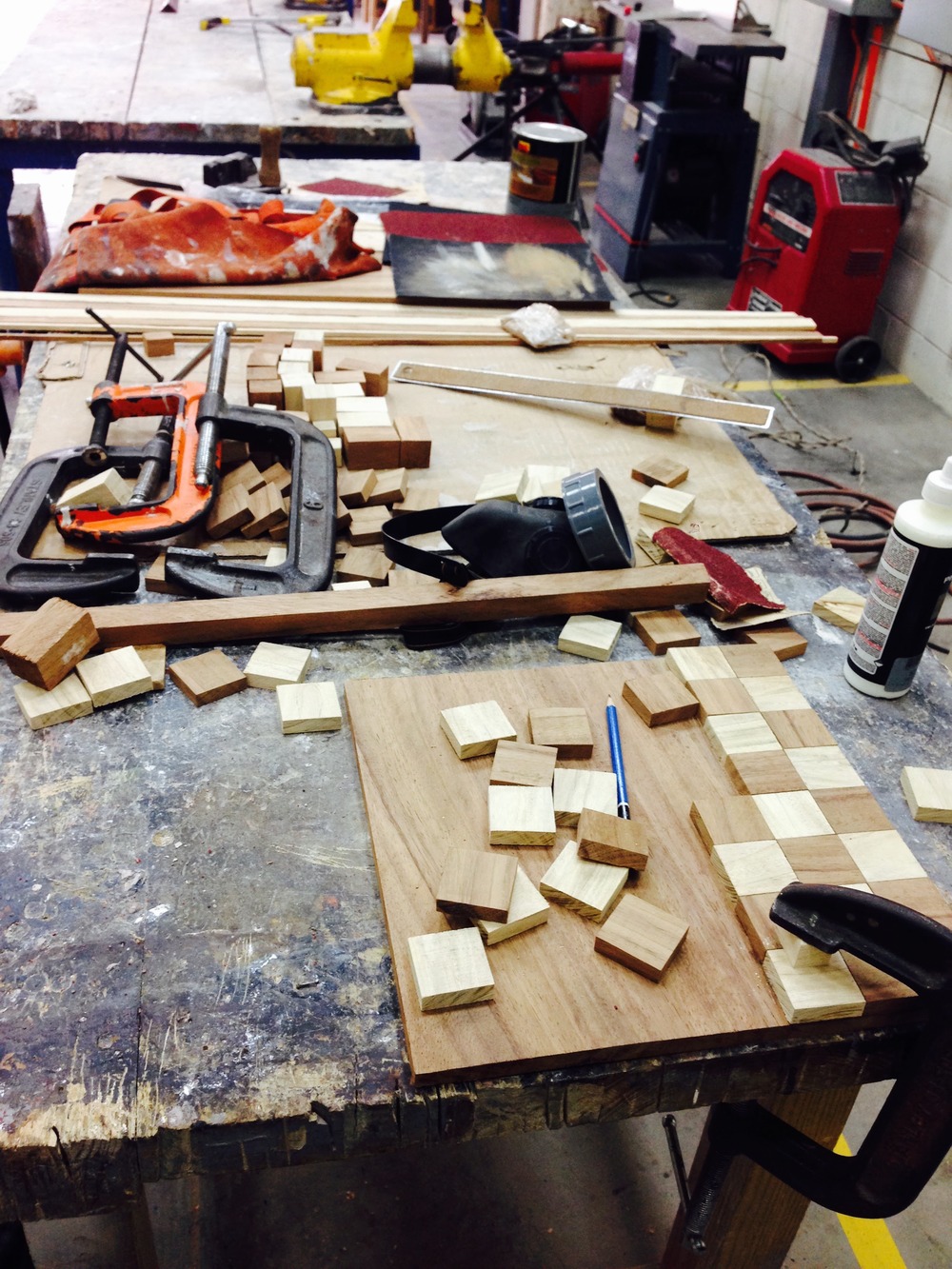 Squares cut from Conacaste and Palo Blanco laid out on the workbench with clamps and tools, checker pattern forming