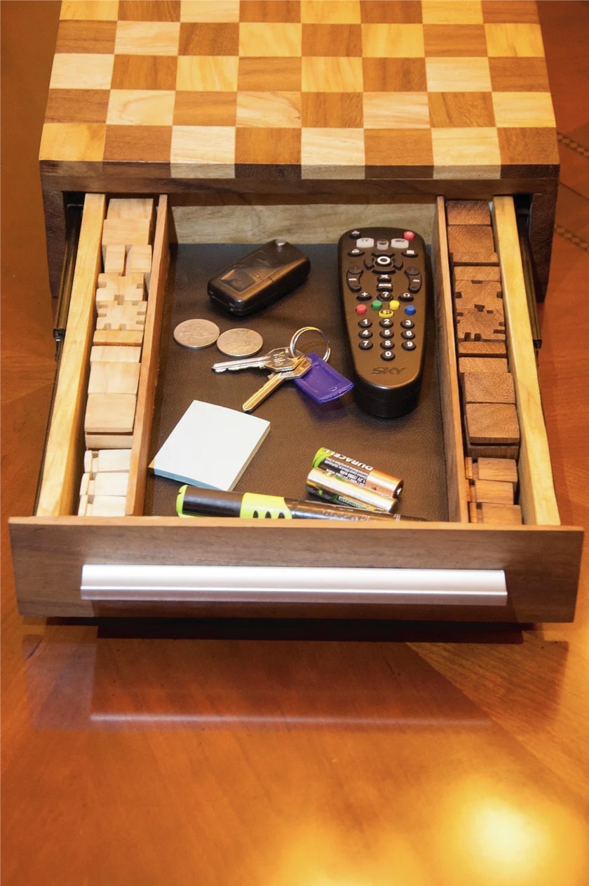 The chessboard's drawer pulled open, showing all the pieces stored in their own compartments