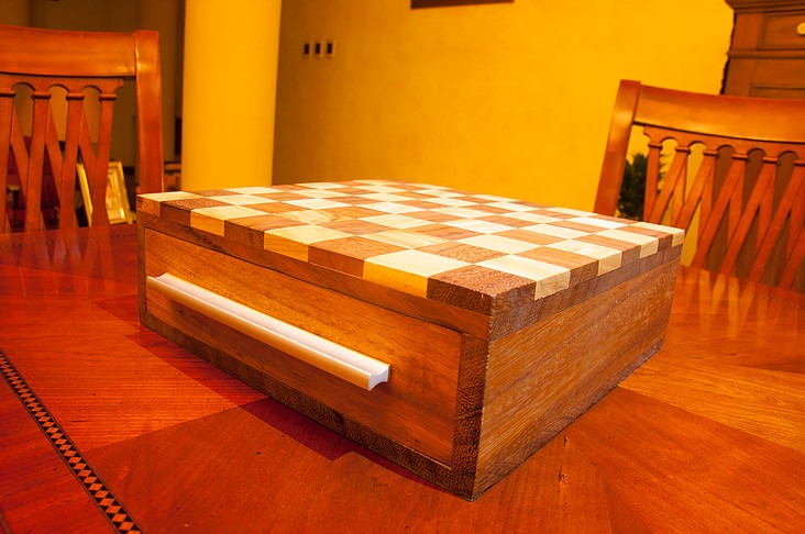 The chessboard closed, sitting as a box on a dining table between chairs